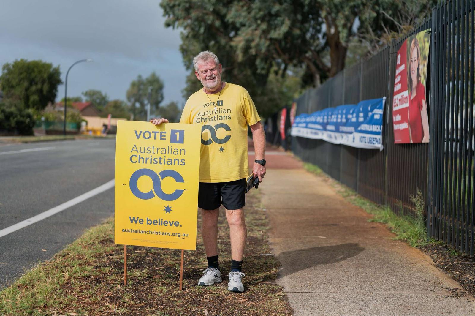 Volunteer holding an Australian Christians sign on a suburban street